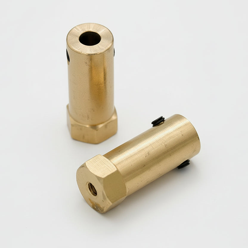 Two brass hex couplings lying on a surface, one with the hexagonal end facing up and the other showing the shaft end.