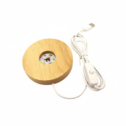 A circular wooden LED under-cabinet light with a white power cord and switch, shown on a plain white background.