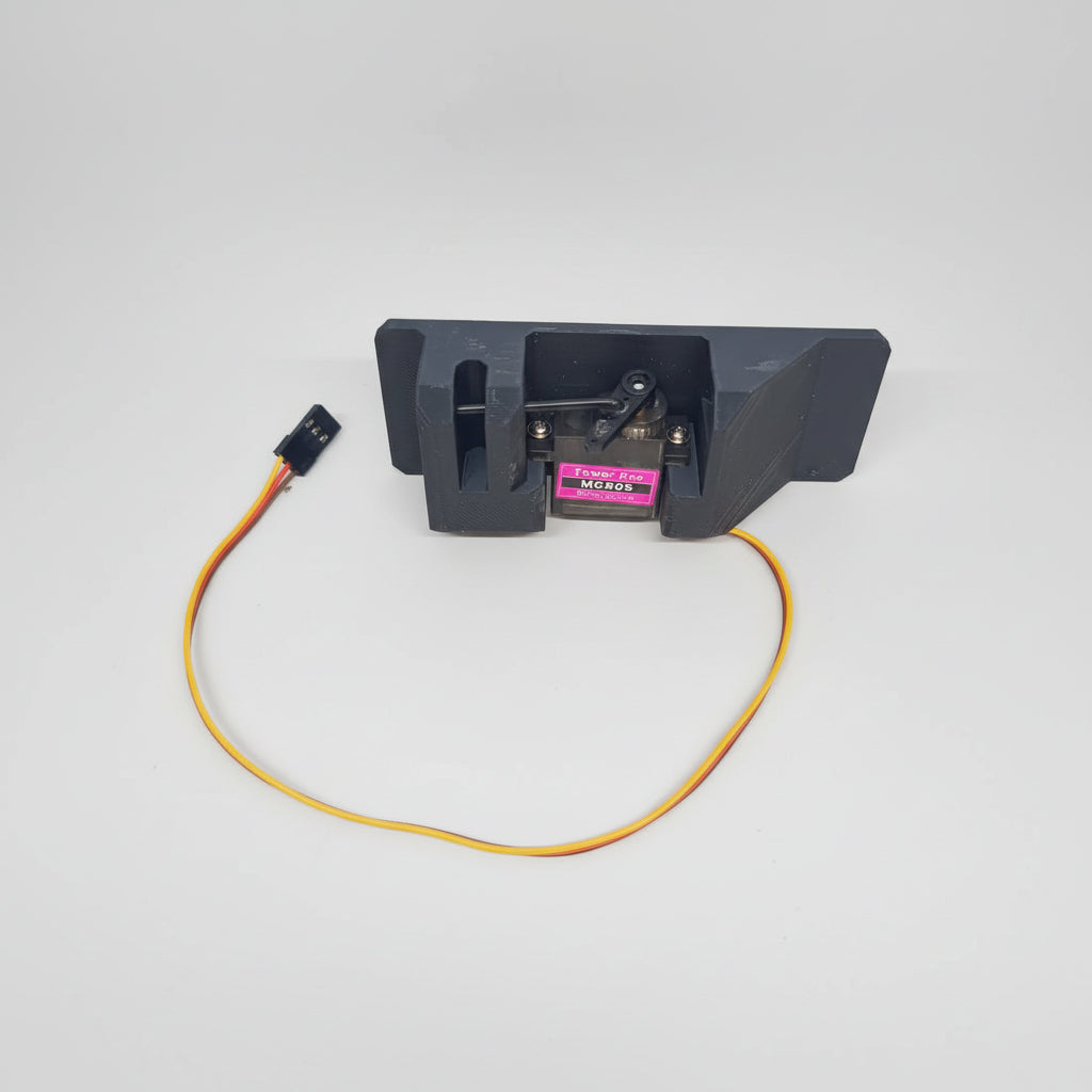 A black servo dispenser air drop rack kit with an attached orange wire and a MG90 servo motor.