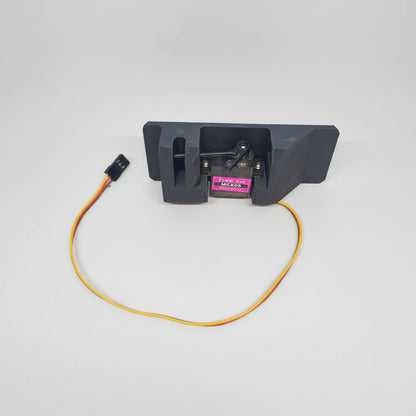 A black servo dispenser air drop rack kit with an attached orange wire and a MG90 servo motor.