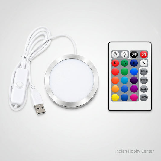 A round LED light strip kit with a white USB cable, white inline switch, and a white remote control featuring colorful buttons for red, green, blue, white, flash, strobe, fade, and smooth.