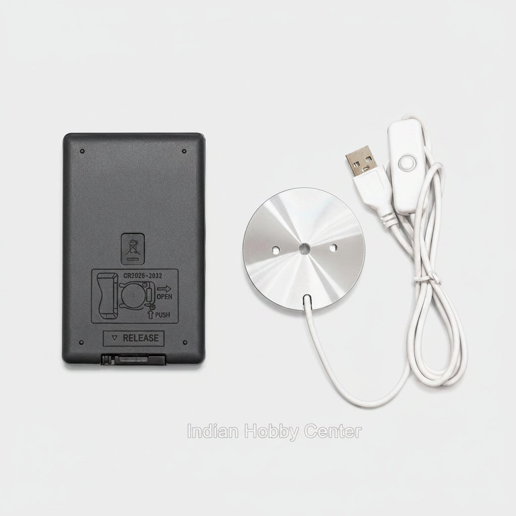 A wireless remote control kit featuring a round brushed silver metal transmitter and a white wired remote with a USB connector, shown next to a black rectangular battery or power unit on a plain white background.