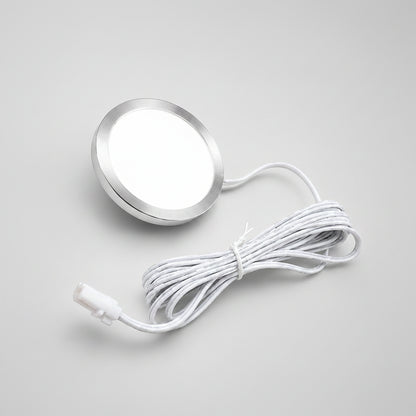 A round silver LED light panel with a white diffuser and a coiled white power cord, shown on a solid beige background.