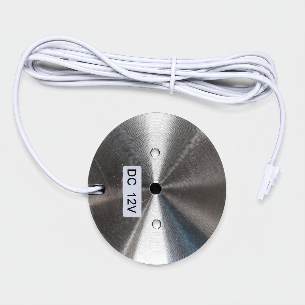 A round brushed-metal sensor module with a white cable and connector, labeled 'DC 12V', on a light gray background.